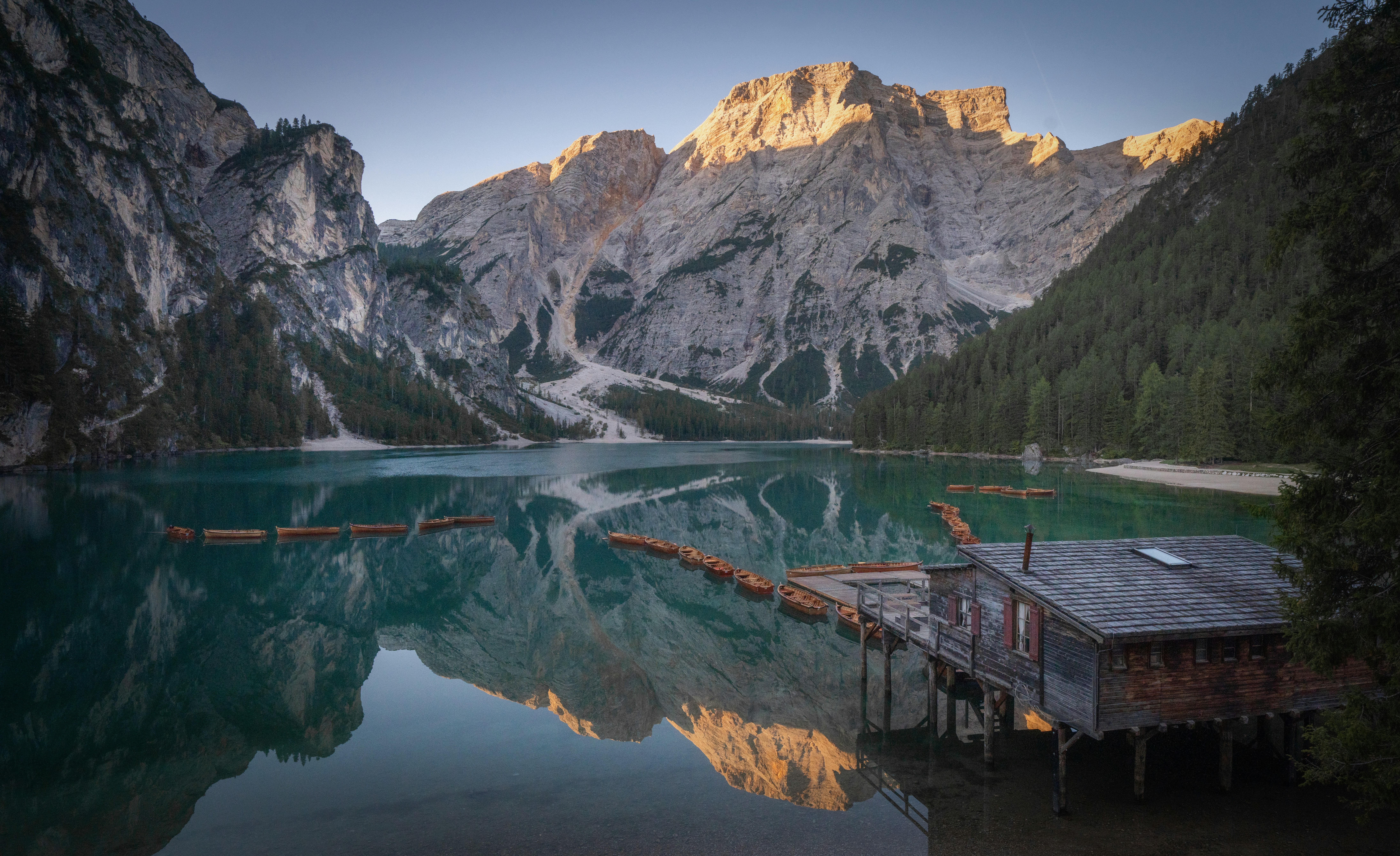 Lesena barka na Lago di Braies ob jutranji zlati svetlobi Dolomiti Italija 2026
